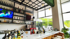A modern bar area with a long counter, wooden chairs, and a variety of liquor bottles.