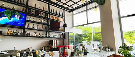 A modern bar area with a long counter, wooden chairs, and a variety of liquor bottles.