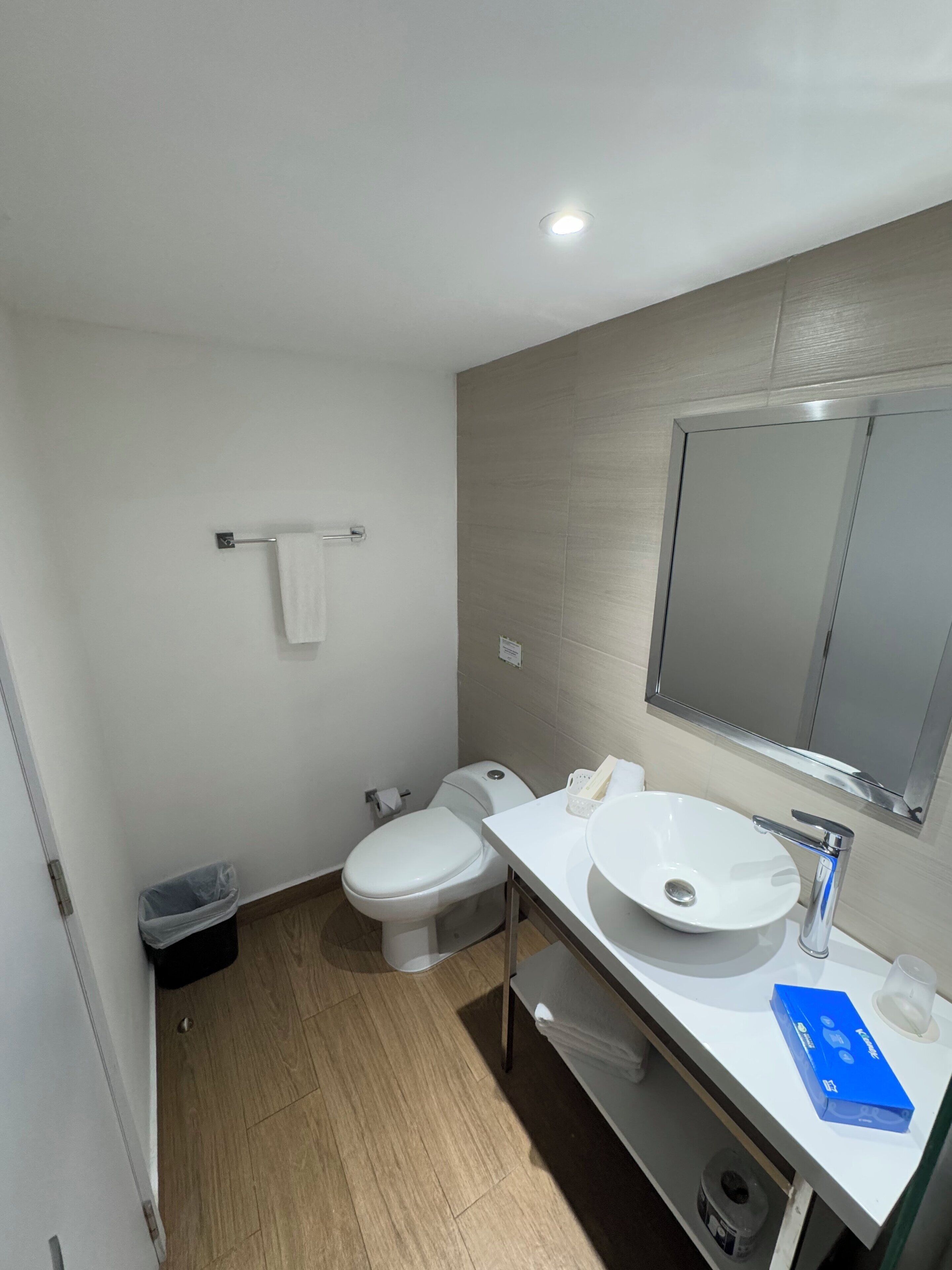 Et moderne badeværelse med toilet, vask og spejl.