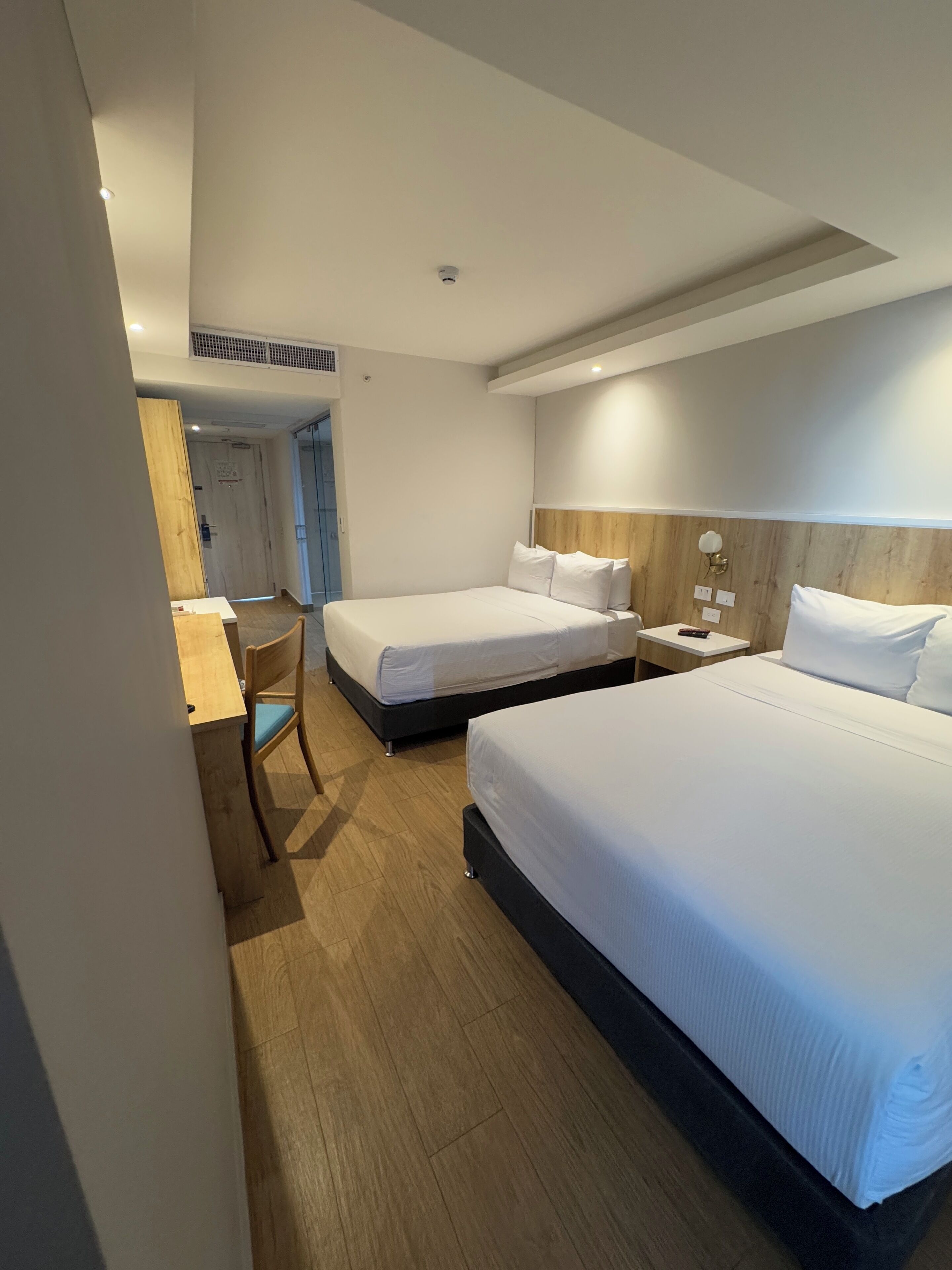 Une chambre d’hôtel avec deux lits, un bureau et une chaise.