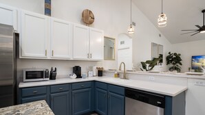 Una cocina moderna con armarios blancos y azules, electrodomésticos de acero inoxidable y una encimera de granito.