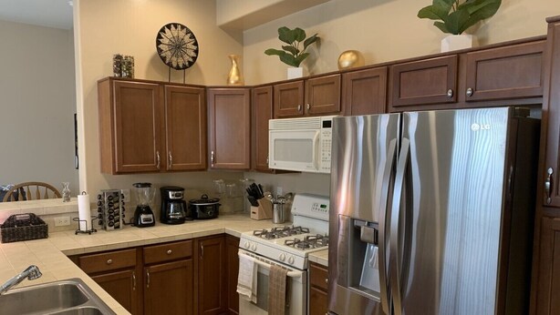 A kitchen with wooden cabinets, a stainless steel refrigerator, a stove, and a microwave. - Rancho Vistoso Getaway (Oro Valley)
