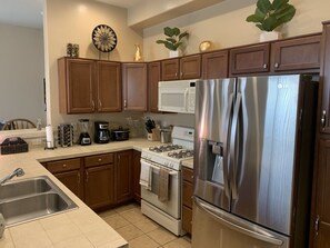 Une cuisine avec des meubles en bois, un réfrigérateur en acier inoxydable, une cuisinière et un four à micro-ondes.