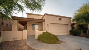A single-story house with a garage, a covered entryway, and a landscaped front yard with a small bush. - Rancho Vistoso Getaway (Oro Valley)