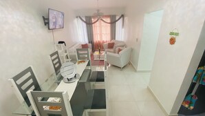 Una sala de estar moderna con comedor, muebles blancos y una araña.