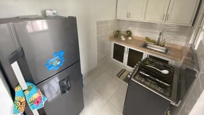 Una cocina compacta con refrigerador, estufa y alacenas.