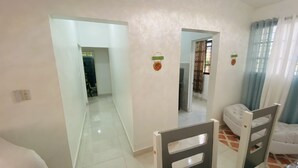 Una habitación con una cama, una silla, una mesita y una puerta que da a otra estancia.