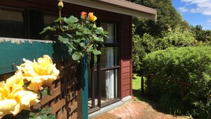 A house with a brick pathway leading to a wooden fence with yellow roses. - Queen Charlotte Secret Oasis, Marlborough Sounds. (Linkwater)