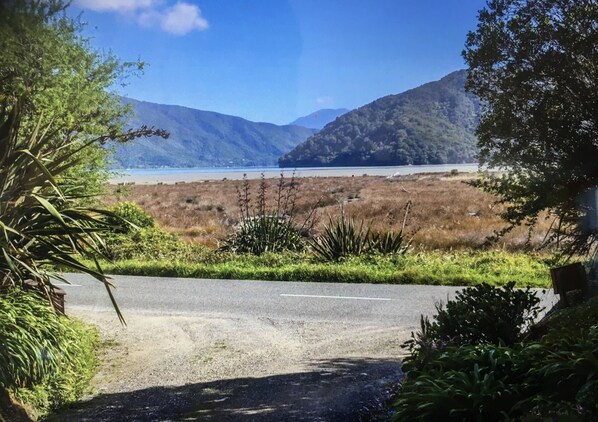 A road leading to a natural landscape with a body of water and hills in the background.