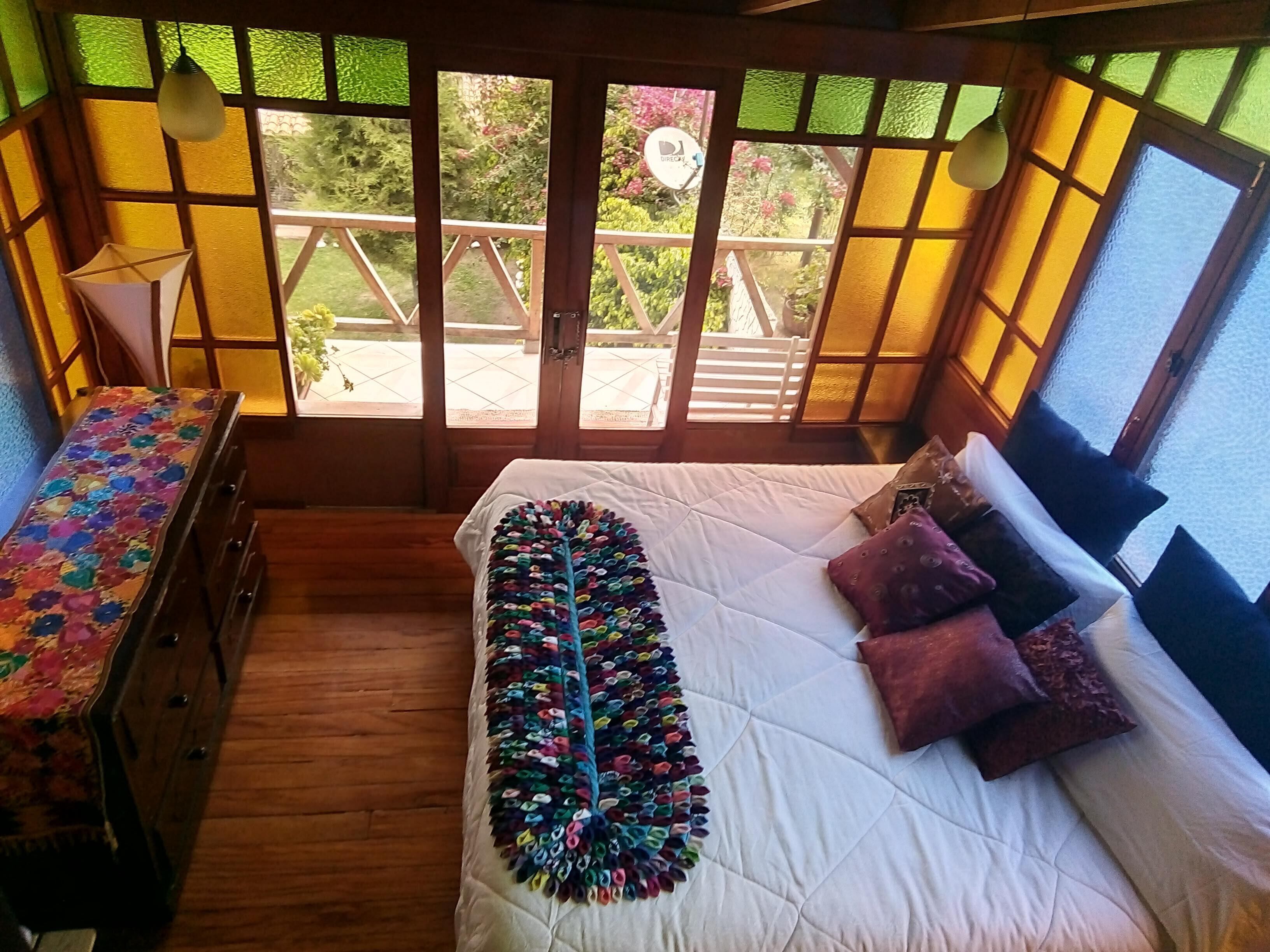 A room with a bed, a dresser, and a window with a view of a garden.