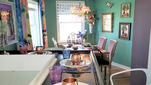 A dining area with a long table set for a meal, chairs around, and a window with blinds. - Fairport Village Triangle Home on the Erie Canal (Fairport)