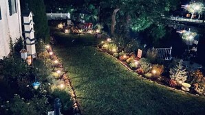 A well-lit garden with a pathway, decorative lights, and a small pond. - Fairport Village Triangle Home on the Erie Canal (Fairport)