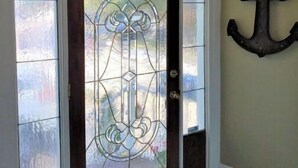 A front door with a decorative glass panel, a wall-mounted anchor decoration, and a ceiling light fixture. - Fairport Village Triangle Home on the Erie Canal (Fairport)