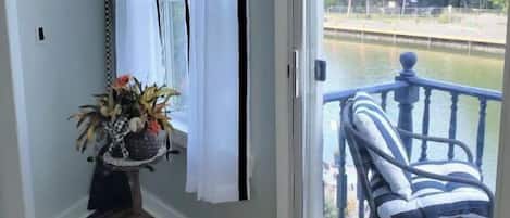 Una habitación con vista a un cuerpo de agua, una silla, una mesita con una planta y una alfombra.