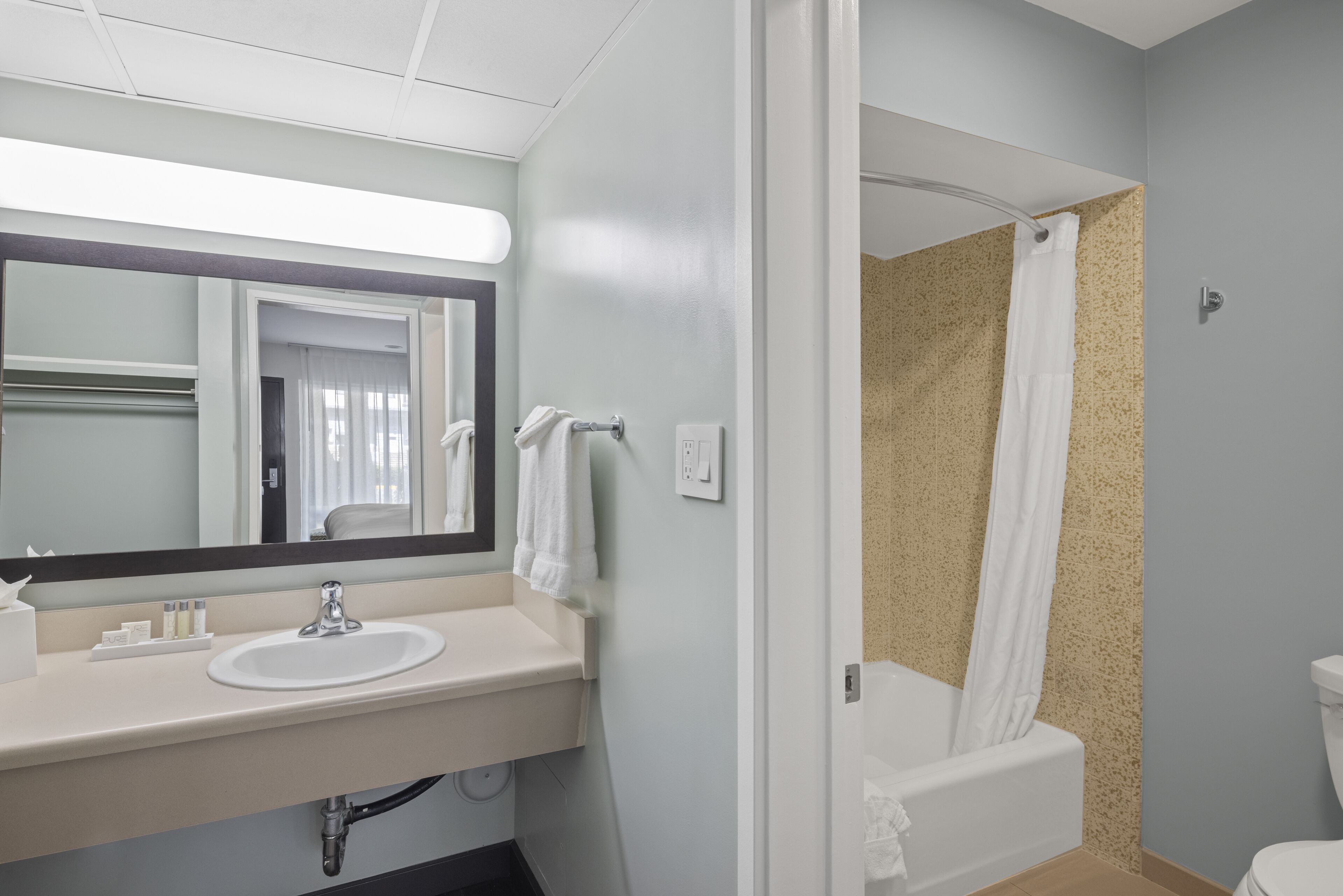 A bathroom with a sink, mirror, and shower curtain.