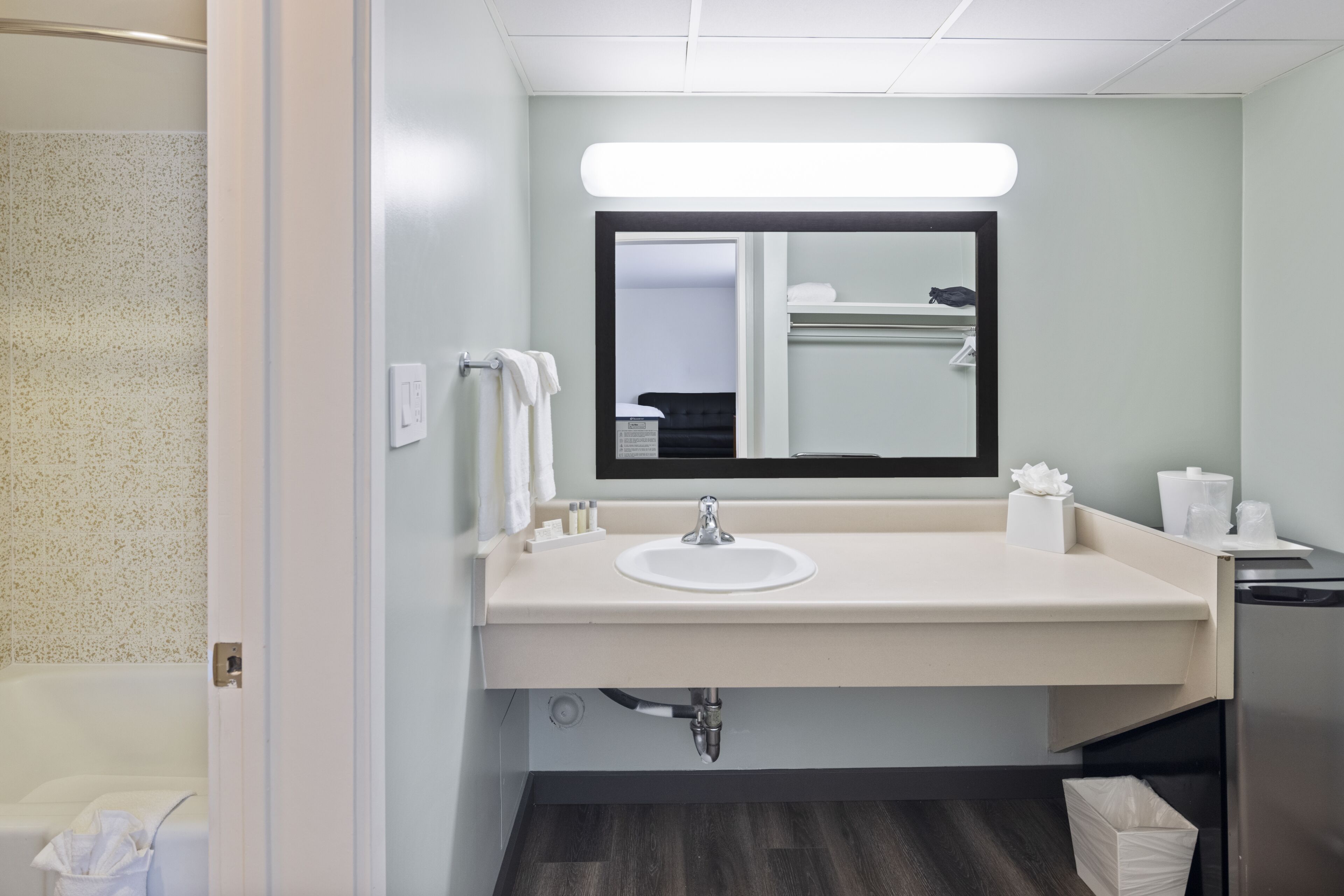 Un baño moderno con lavamanos blanco, espejo y toallero.