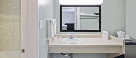 Un baño moderno con lavamanos blanco, espejo y toallero.