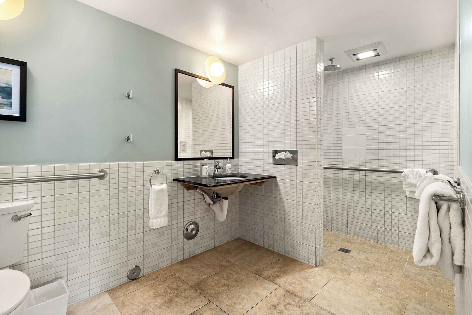 A modern bathroom with a toilet, sink, mirror, and shower.