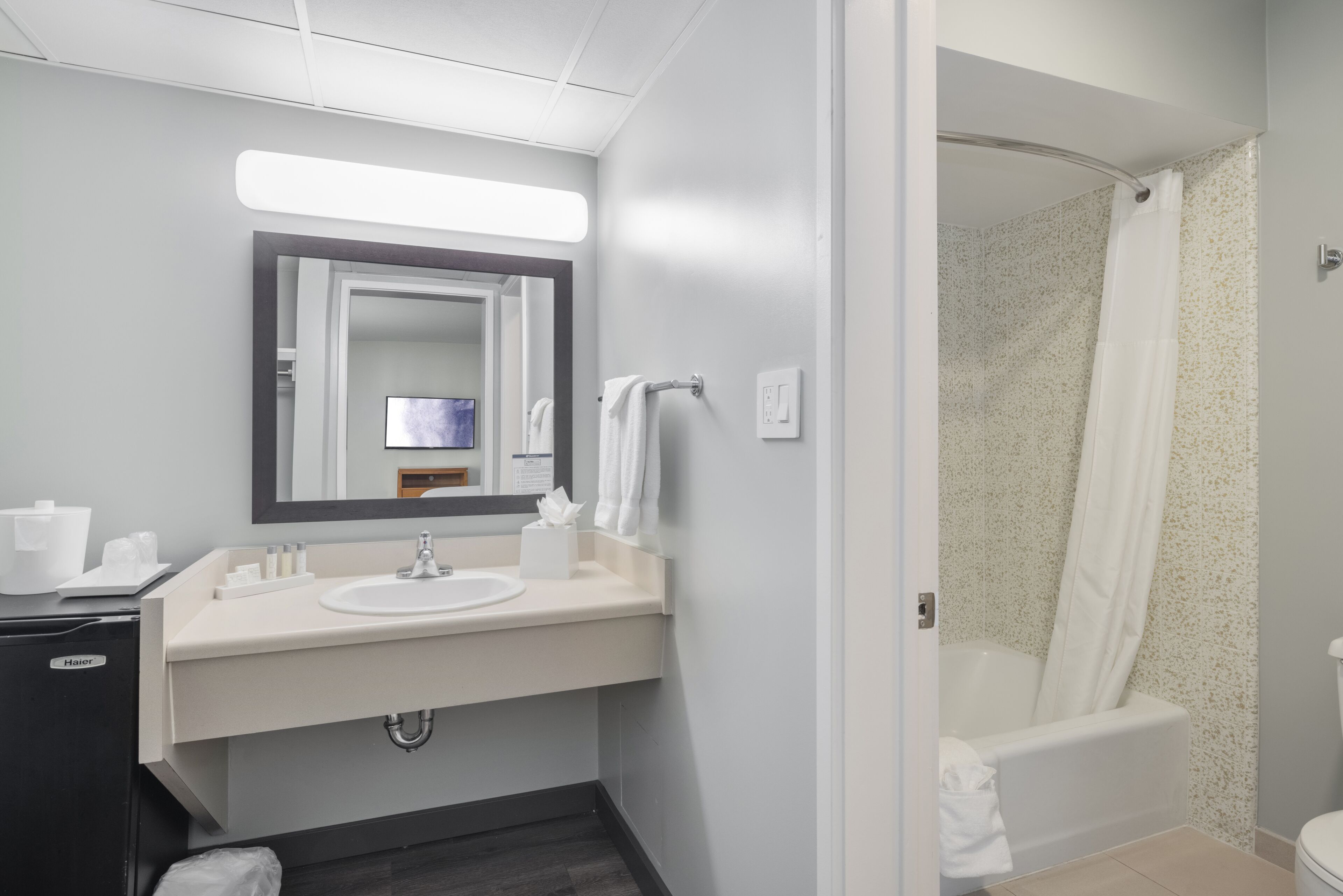Un baño moderno con lavamanos, espejo y ducha.