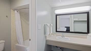 A bathroom with a shower, toilet, sink, and mirror.