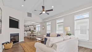 Un salon spacieux avec un canapé blanc, une cheminée et un ventilateur de plafond.