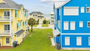 Une rangée de bâtiments colorés situés en bord de mer, avec une pelouse verdoyante et une vue dégagée sur l’océan.