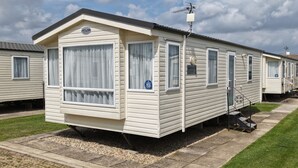 Een rij mobiele woningen met plat dak, grote ramen en een klein terras.