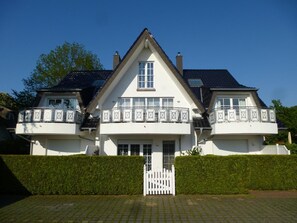 A two-story house with a symmetrical facade, a central entrance, and a white picket fence.