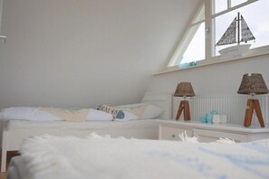 Une chambre à coucher avec un lit, une table de chevet, une lampe et une fenêtre décorée avec un motif de voilier.