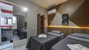 Una habitación de hotel con dos camas, un baño con lavabo y un espejo.