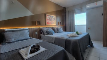Ein Hotelzimmer mit zwei Betten, einem Bild an der Wand, einer Klimaanlage und einem Vorhangfenster.