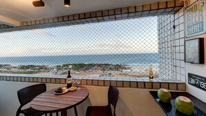 Un balcón con una mesa dispuesta para dos, una botella de cerveza y un plato de uvas.