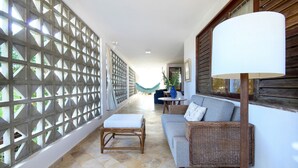 A corridor with a wicker sofa, a small table, and a lamp.