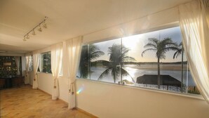 A room with a large window overlooking a beach with palm trees and a body of water.