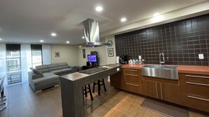 A modern kitchen with a central island, dark tiled backsplash, and a built-in stove.