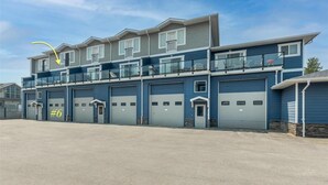 A multi-story building with a garage on the ground floor, a balcony on the second floor, and a clear sky.