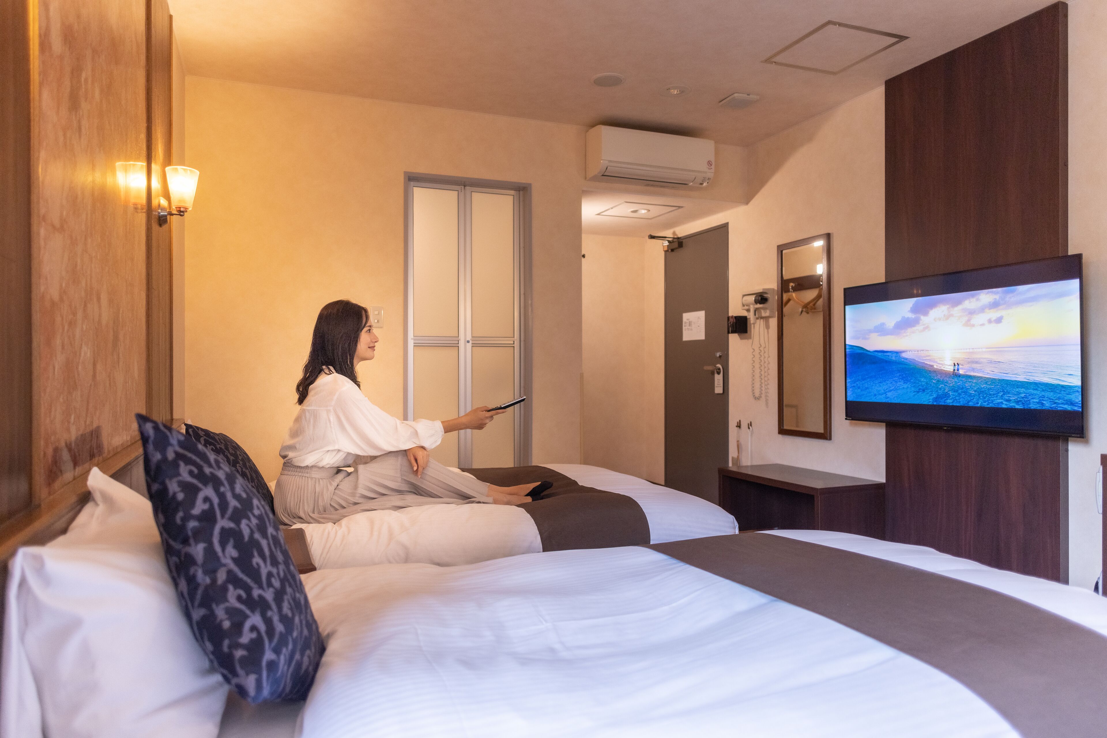 A hotel room with a bed, a television, and a door.