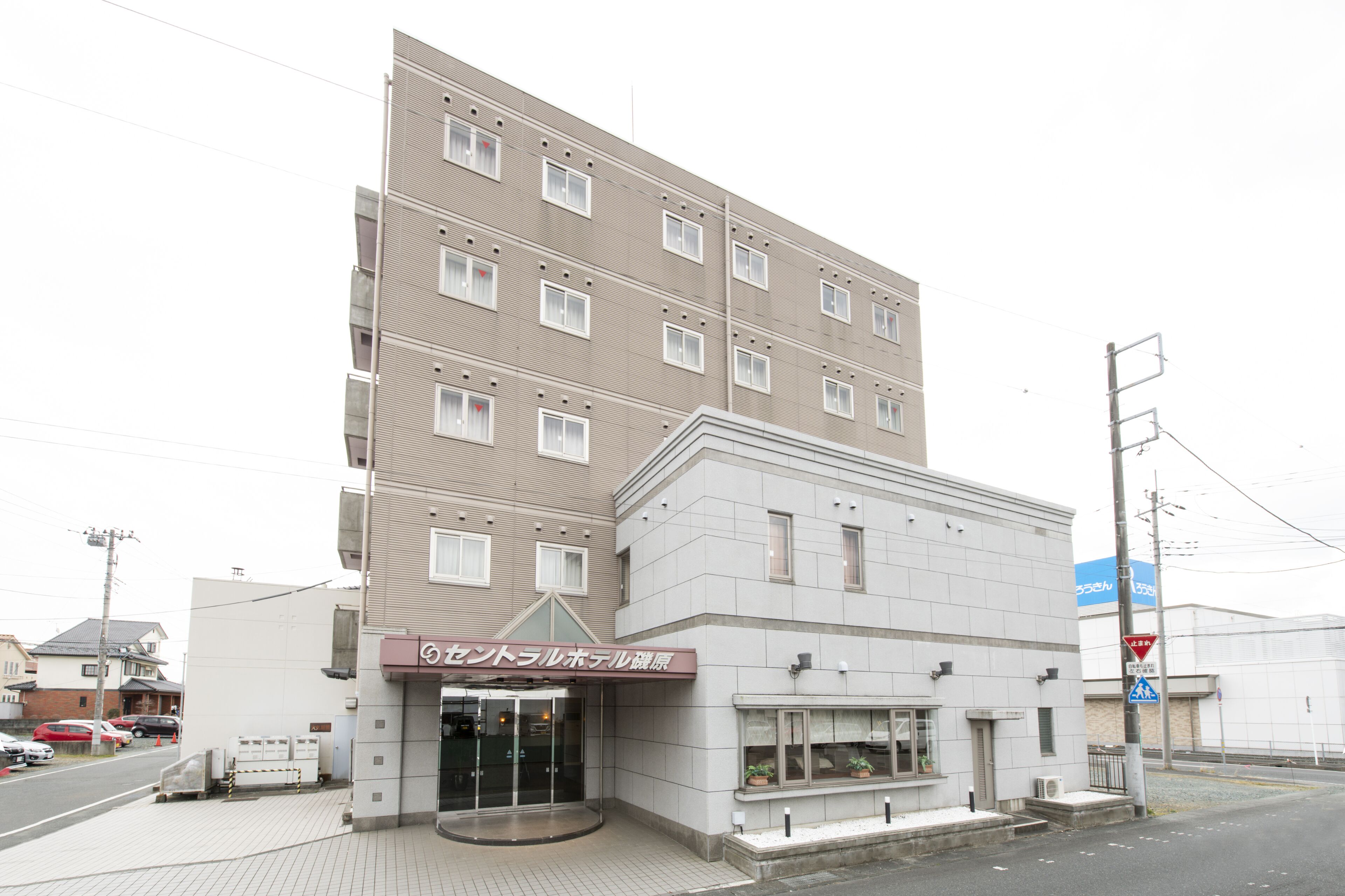 A multi-story hotel with a modern design, featuring a prominent entrance with a glass door and a sign in a foreign language.