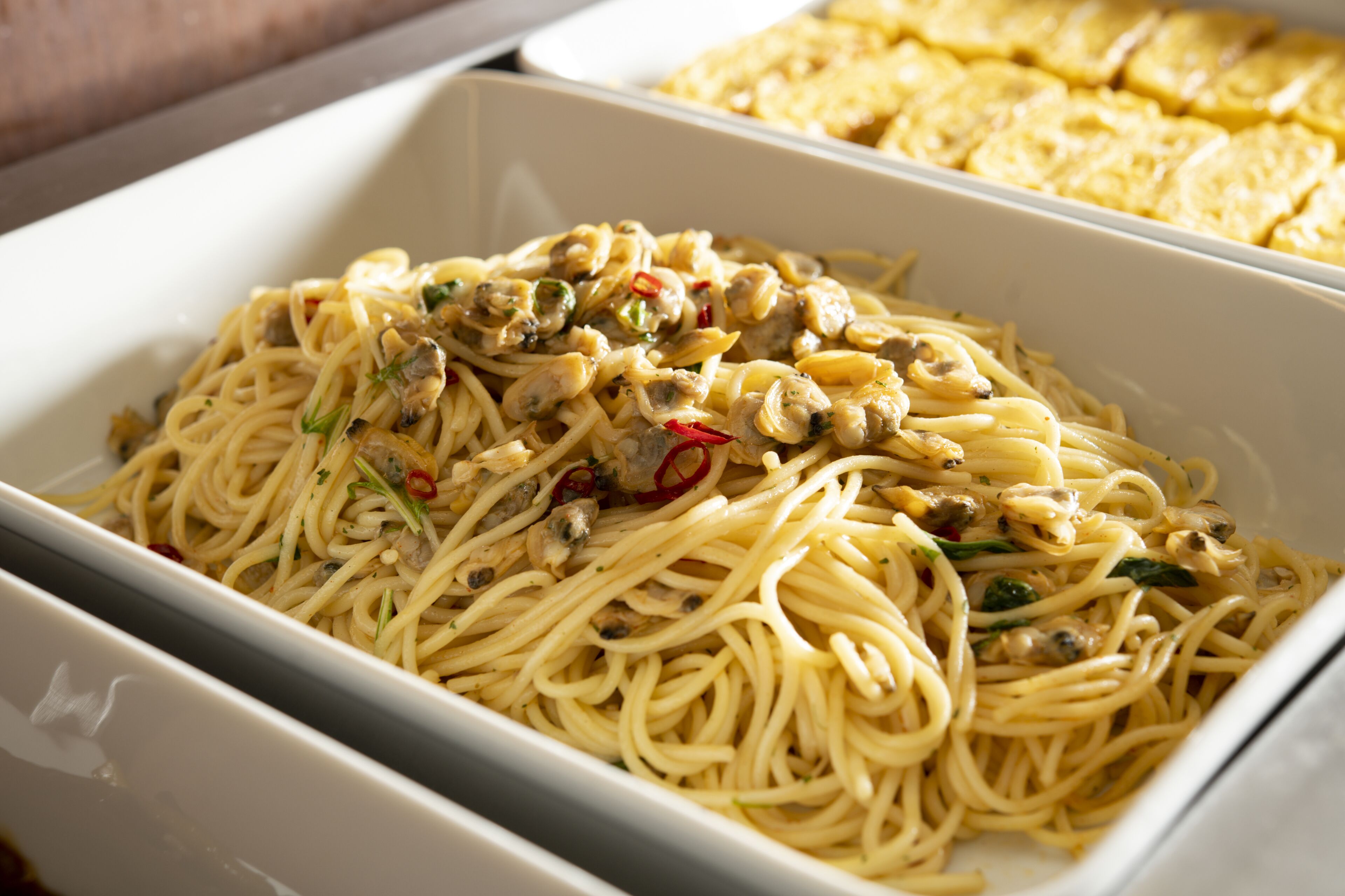 A rectangular white dish containing spaghetti with mushrooms and herbs.