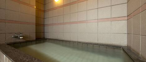 A modern bathroom with a rectangular bathtub, tiled walls, and two wall-mounted lights.