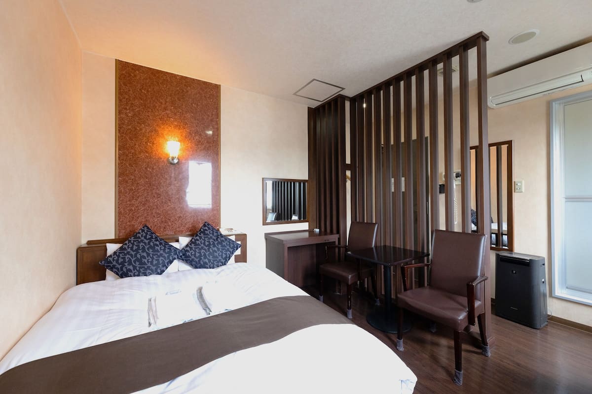 Une chambre d’hôtel avec un lit, un bureau, une chaise, une télévision et une fenêtre.