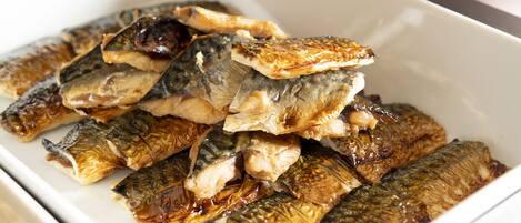 Un contenitore rettangolare bianco pieno di pesce alla griglia.