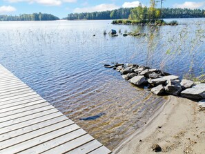 A wooden dock extending into a calm lake with clear water, surrounded by rocks and vegetation. - Suvituuli by Interhome (Liperi)