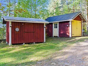 Two small wooden sheds with metal roofs, one red and one yellow, situated on a grassy area with trees in the background. - Suvituuli by Interhome (Liperi)