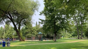 Un parc amb un àrea de jocs, un kiosc i un camí per passejar.