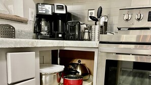 Une cuisine équipée d’un four encastré, d’une machine à café et d’une bouilloire posée sur le plan de travail.