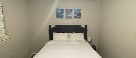 Un dormitorio con cama, ventilador de techo y dos cuadros en la pared.