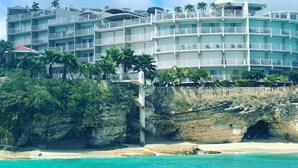 A multi-story hotel with balconies, located near a beach with clear turquoise water. - Tranquil Oceanside: Pools & Direct Beach Access (Sint Maarten)