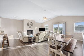 Relax in this spacious living area with a high ceiling, ceiling fan, and comfortable seating for dining and relaxation.