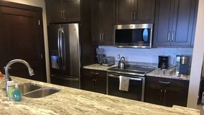 A kitchen with dark cabinets, stainless steel appliances, a granite countertop, and a stainless steel sink. - Luxury Windham Mtn Slope Side 3 BDRM Condo (Windham)